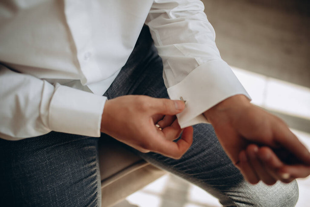 man buttons shirt, a man in a white shirt, morning groom, hands of a man close-up, a white shirt on a businessman, man buttons shirt sleeve, businessman puts on a suit - Photo, image