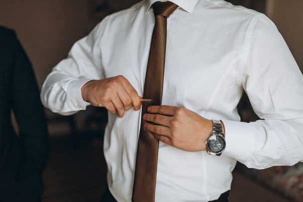 man in shirt dressing up and adjusting tie on neck at home - Foto, Bild