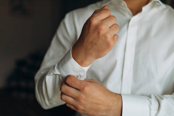man buttons shirt, a man in a white shirt, morning groom, hands of a man close-up, a white shirt on a businessman, man buttons shirt sleeve, businessman puts on a suit - Фото, зображення