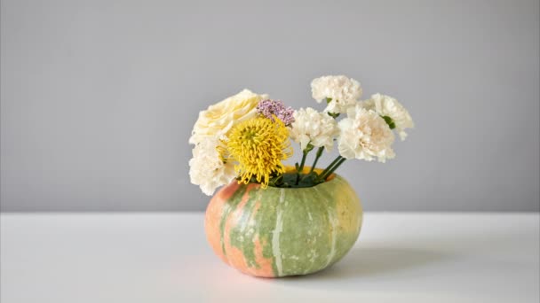 Stop motion, step by step installation of flowers arrangement in pumpkin on the white table. Fresh cut flowers for decoration home. European floral shop. Delivery fresh cut flower. - Footage, Video
