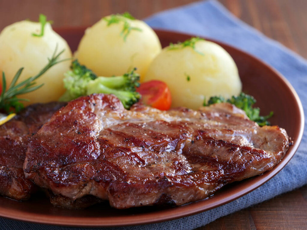 Bistecca di maiale succosa con patate bollite e rosmarino sul piatto - Foto, immagini