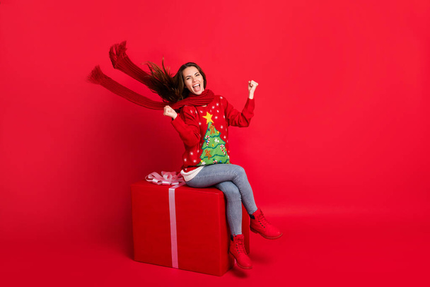 Full length body size view of her she attractive lucky cheerful glad girl sitting on big giftbox season rejoicing celebratory win winner isolated bright vivid shine vibrant red color background - Photo, Image