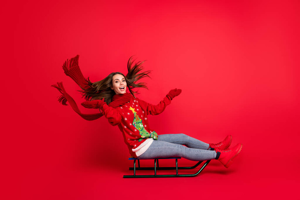 Full length body size profile side view of her she attractive cheerful cheery glad girl riding sledge having fun vacation christmastime isolated bright vivid shine vibrant red color background - Foto, imagen