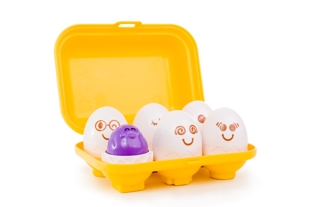 Открытый поднос из пластиковых игрушечных яиц на белом фоне
 - Фото, изображение