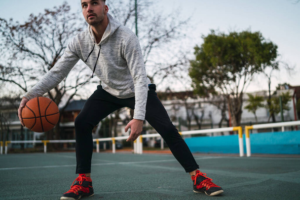 Portrait of young basketball player playing outdoors. Sport concept. Basketball concept. - 写真・画像