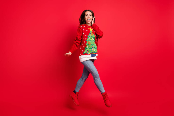 Full length body size view of her she attractive slim skinny amazed glad cheerful girl jumping having fun walking wear casual jeans look outfit isolated bright vivid shine vibrant red color background - 写真・画像