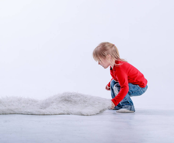 Egy szőke kislány téli pulóverben pózol a stúdióban. - Fotó, kép