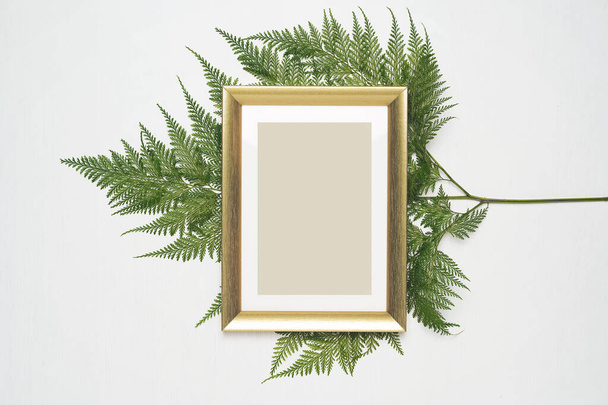 Stylish minimal composition with photo frame and green leaves on a white wooden background. Empty photo frame and green leaves. flat lay, top view. - Foto, immagini