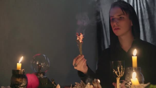 Ein männlicher Wahrsager in einem magischen Salon zündet Weihrauch an und bewegt Hand für paranormales Ritual - Filmmaterial, Video