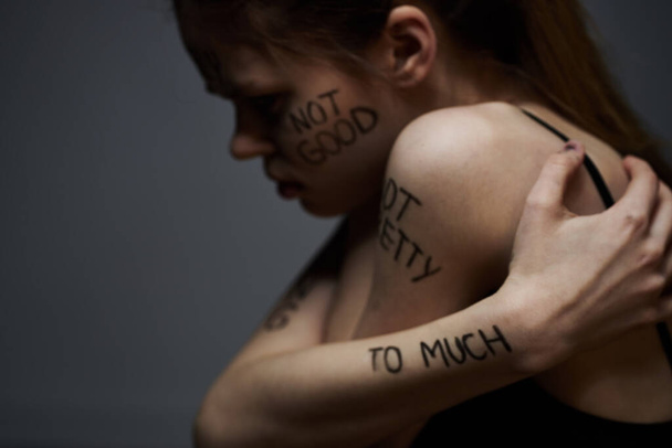 Emocjonalna kobieta z napisami na jej ciele gesty z rąk styl życia frustracja stres szare tło - Zdjęcie, obraz