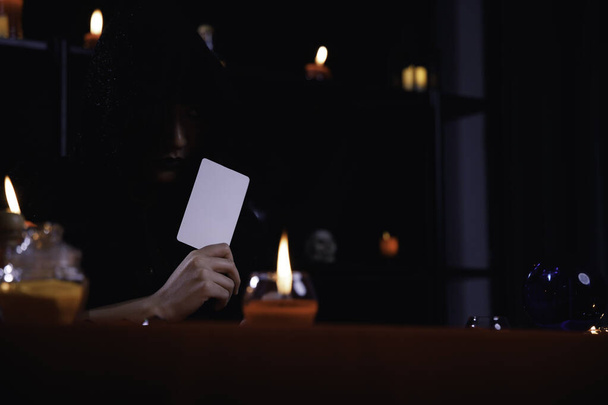 Μυστηριώδης μάντης με μαύρη κουκούλα που διαβάζει ταρώ για να προβλέψει τη μοίρα ή το πεπρωμένο.. - Φωτογραφία, εικόνα