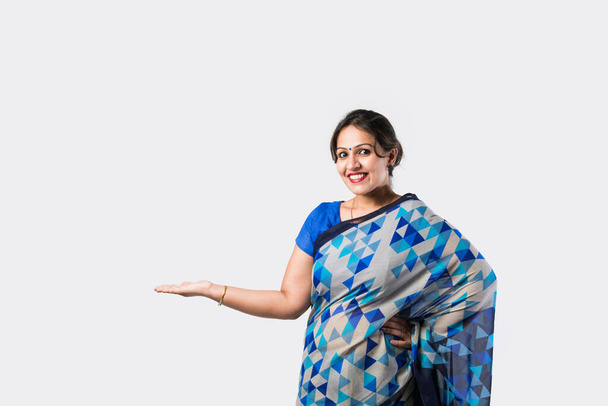 Улыбающаяся привлекательная индийская женщина на сари демонстрирует Copyspace на белом фоне - Фото, изображение