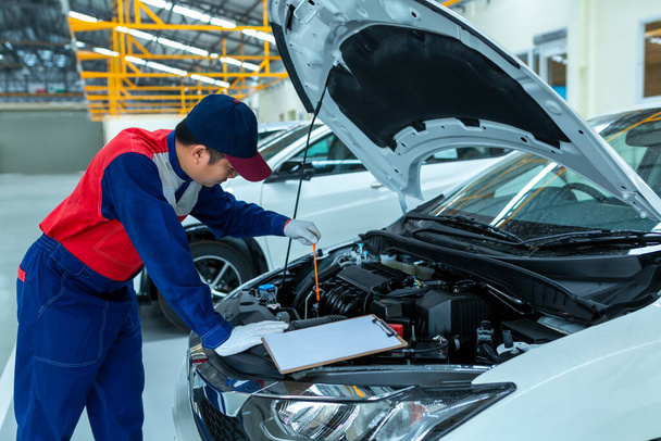 Auto monteur controleren auto motorolie in auto auto reparatie service center. - Foto, afbeelding