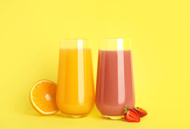 Glasses of delicious juices and fresh fruits on yellow background - Foto, afbeelding