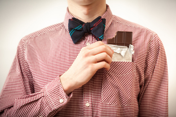 Чоловік у сорочці та краватці, що виймає шоколад із грудей
 - Фото, зображення