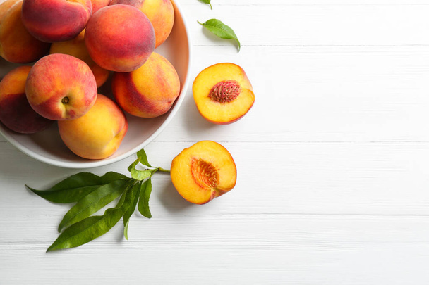 Fresh sweet peaches on white wooden table, flat lay. Space for text - Zdjęcie, obraz