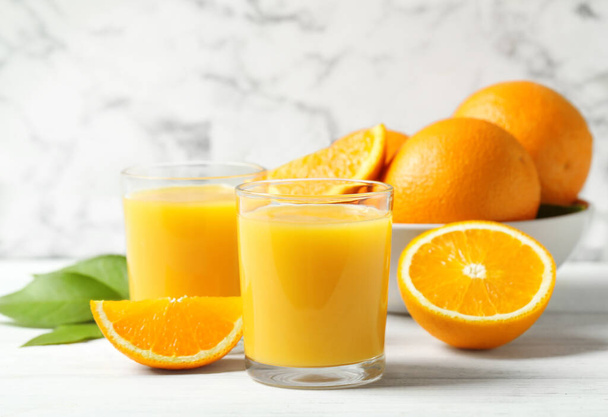 Glasses of orange juice and fresh fruits on white table - Zdjęcie, obraz