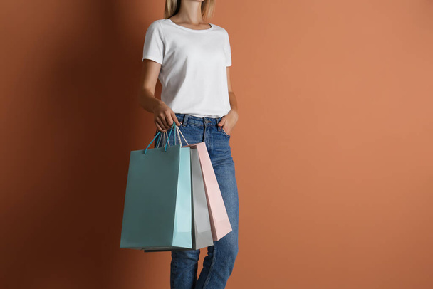 Woman with paper shopping bags on light brown background, closeup - Foto, Imagen