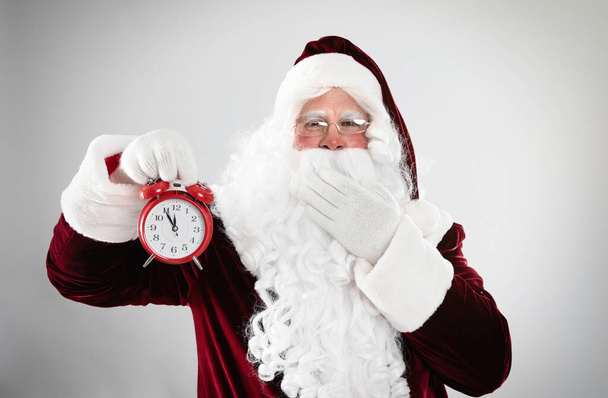 Santa Claus holding alarm clock on light grey background. Christmas countdown - Φωτογραφία, εικόνα