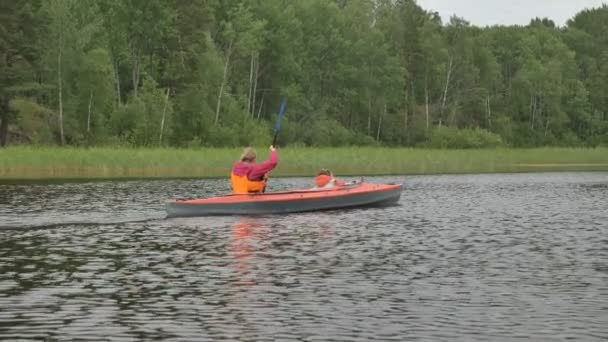 vrouw rijen kleine kajak met kind zeilen langs groot meer - Video