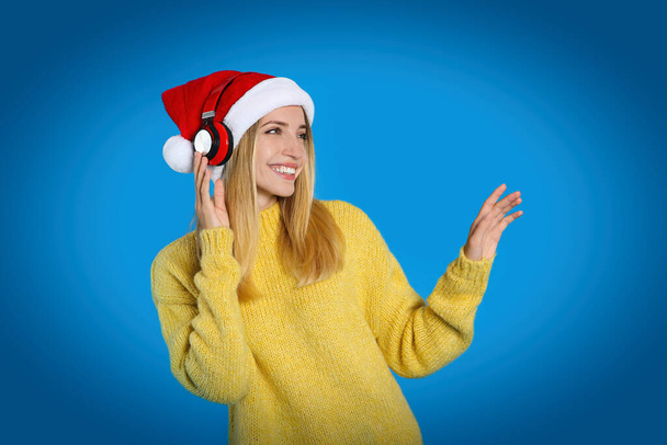 Happy woman with headphones on blue background. Christmas music - Foto, immagini