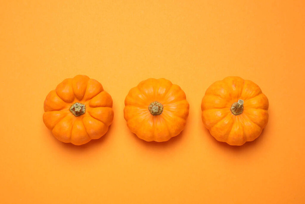 Fresh ripe pumpkins on orange background, flat lay - Фото, изображение