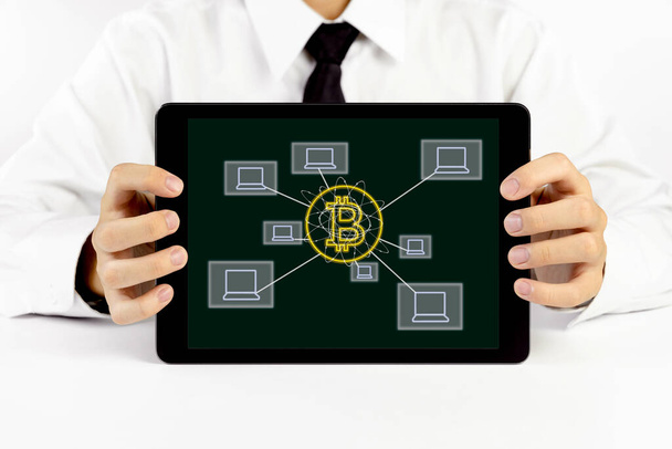 Empresario sosteniendo una tableta con símbolo de bitcoin e iconos de computadora portátil - Foto, imagen