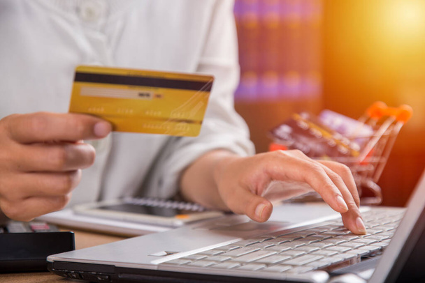 Femme tenant une carte de crédit et utilisant un ordinateur portable. Concept commercial.  - Photo, image