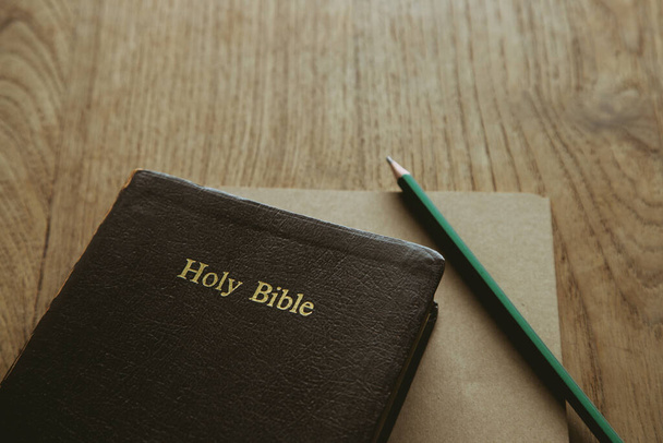 Szent Biblia jegyzetfüzettel és ceruzával a fa asztalon, másolás hely - Fotó, kép