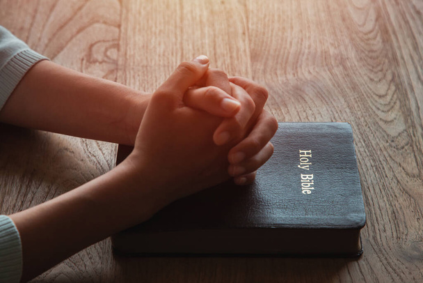 Žena s biblickou modlitbou, ruce sepjaté k sobě na dřevěném stole. - Fotografie, Obrázek