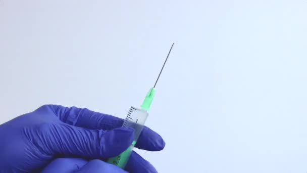 A female hand in a blue medical glove holds a syringe. Close-up. - Footage, Video