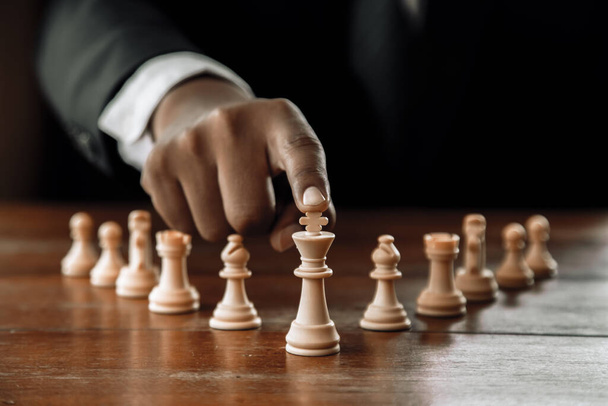 Рука бизнесмена, движущегося шахматной фигурой в игре успеха соревнования. стратегия, тонизированный ретро эффект. - Фото, изображение
