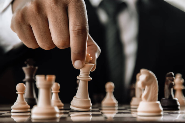 Ręka biznesmena przenoszącego figurę szachową w konkursie sukces gry. strategia, stonowany efekt retro. - Zdjęcie, obraz