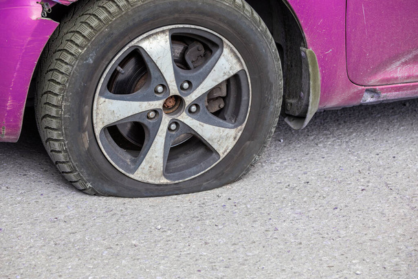 civiele auto platte band close-up op droge zonnige dag op grijs asfalt oppervlak - Foto, afbeelding