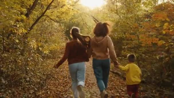Anne ve çocuklar sonbahar ormanında koşuyorlar. - Video, Çekim
