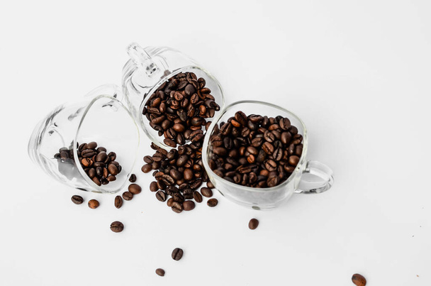 кофейные зёрна в прозрачной чашке на белом фоне - Фото, изображение