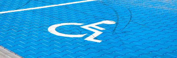 障害者のための空の青い駐車場、地面に車椅子のシンボル、広いパノラマショット。障害者用駐車場。駐車場エリア、屋外、閉鎖。シンプルなアクセシビリティコンセプト - 写真・画像