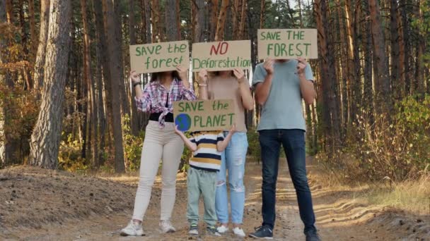 Tiltakozó család plakátokkal az erdőben - Felvétel, videó