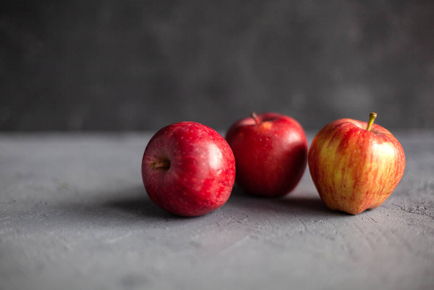 Три спелых садовых красных яблока на сером бетоне. Фруктовая концепция осеннего урожая. Пространство для текста. Селективный мягкий фокус. - Фото, изображение