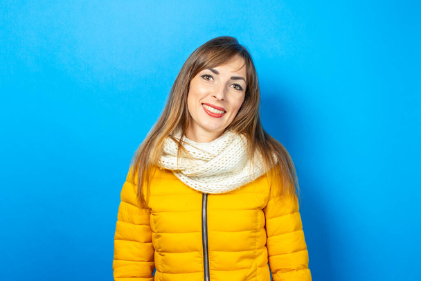 Mavi arka planda poz veren sarı ceketli genç bir kadın. Kış ve sonbahar kavramları, mevsim için kıyafetler. Pankart. - Fotoğraf, Görsel