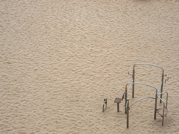 Κάτοψη της άμμου μιας εντελώς άδειας παραλίας, με μηχανήματα υπαίθριας εκπαίδευσης - Φωτογραφία, εικόνα