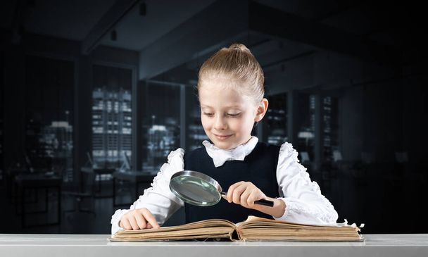Little girl sitting at desk with magnifier - Foto, immagini