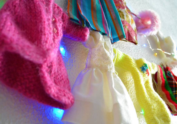 Roupas de boneca penduradas em uma corda com luzes led depois de lavar a roupa de diferentes padrões e formas - Foto, Imagem