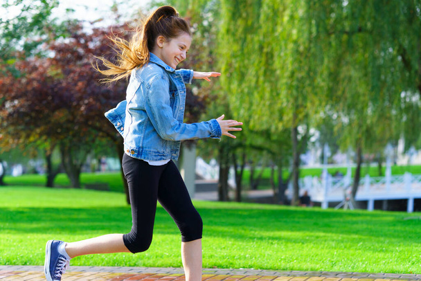 menina corre através de um parque da cidade, dia de verão brilhante - Foto, Imagem