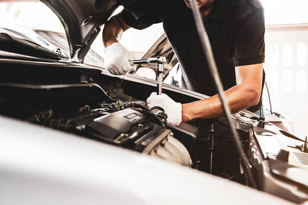 Otomobil tamircisinin yakın çekim elleri araba garajındaki bir araba motorunu tamir etmek için ingiliz anahtarını kullanıyor. Araba bakımı, tamirat ve hizmet kavramları. - Fotoğraf, Görsel