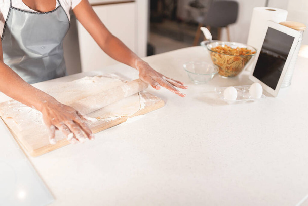 Woman rolling dough in the kitchen - Fotó, kép