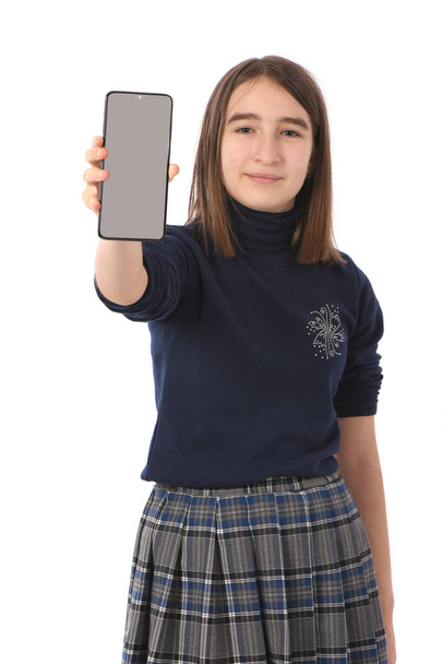 Chica pre-adolescente sosteniendo teléfono inteligente negro con pantalla en blanco. aislado sobre fondo blanco. Foto de alta resolución. Profundidad total del campo. - Foto, imagen