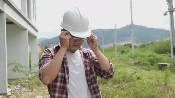 Lassú felvételek az építési terület ellenőrzéséről, ázsiai mérnökök sisakokban sétálnak az építkezésen és tervrajzokkal ellenőrzik - Felvétel, videó