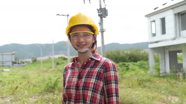 Langzame beelden van het controleren van de bouwplaats, Aziatische vrouwelijke ingenieur in helmen lopen rond de bouwplaats  - Video