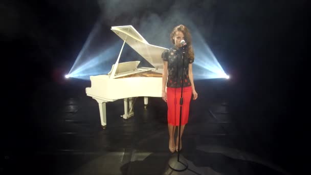 retro lady cantante cantando jazz en el micrófono en el escenario con focos y piano blanco, música. - Imágenes, Vídeo